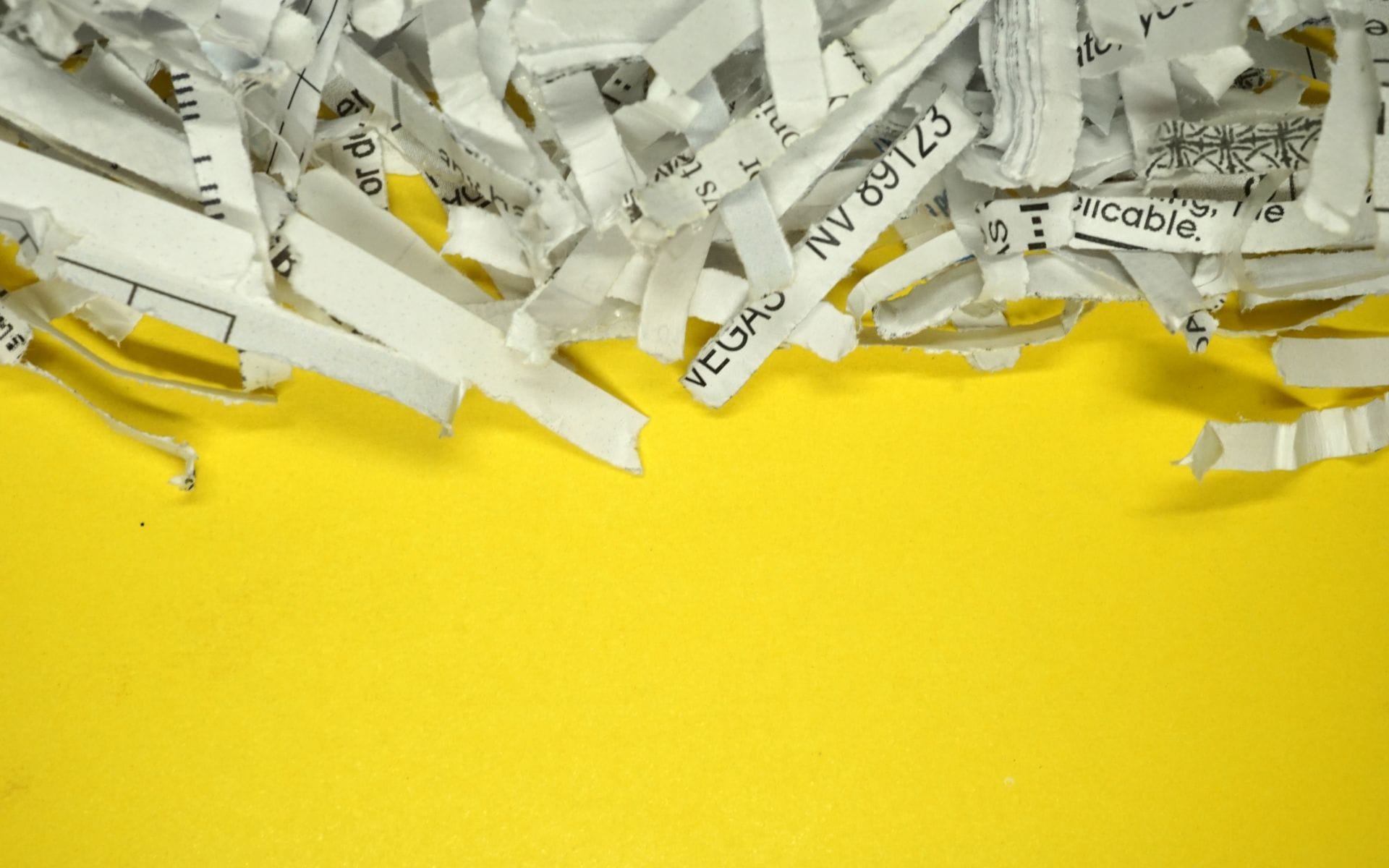Shredded paper strips on bright yellow background.