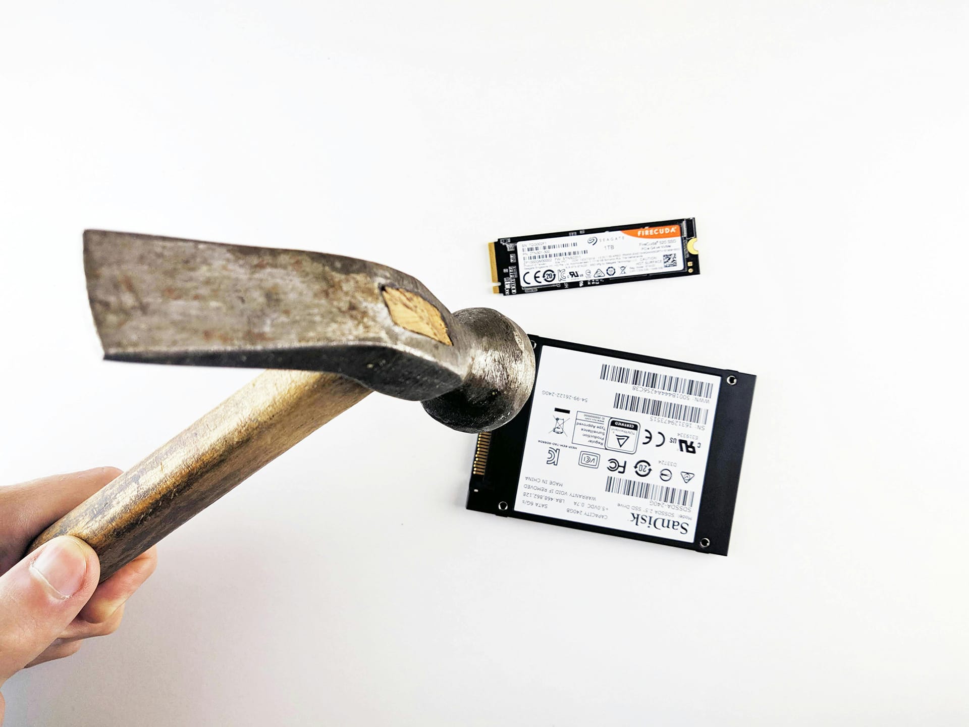 Hammer above two SSD drives, white background.