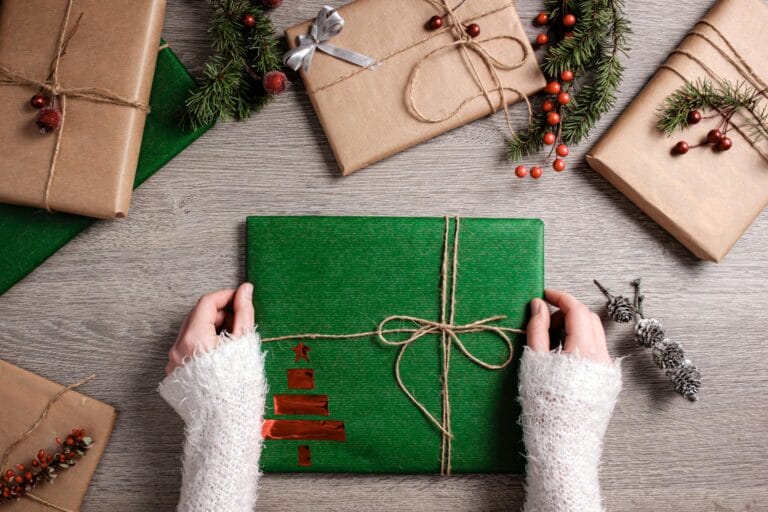 Hands holding wrapped Christmas gifts with decorations.